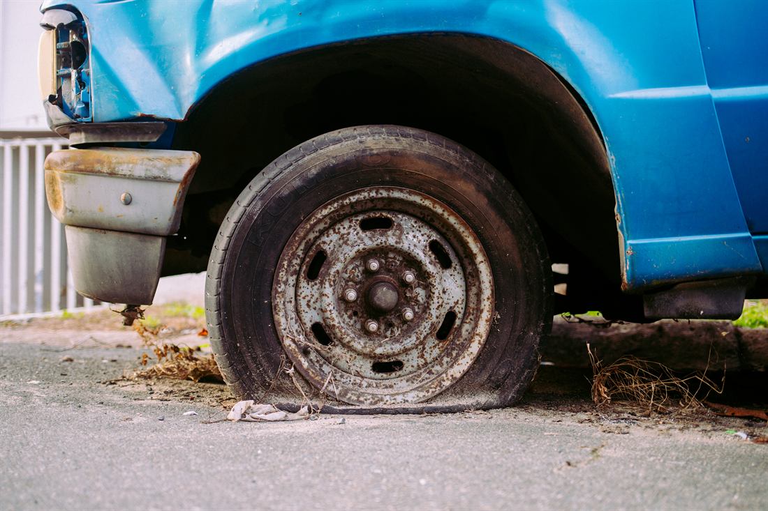 Close-up of a weathered blue truck and rusted wheel