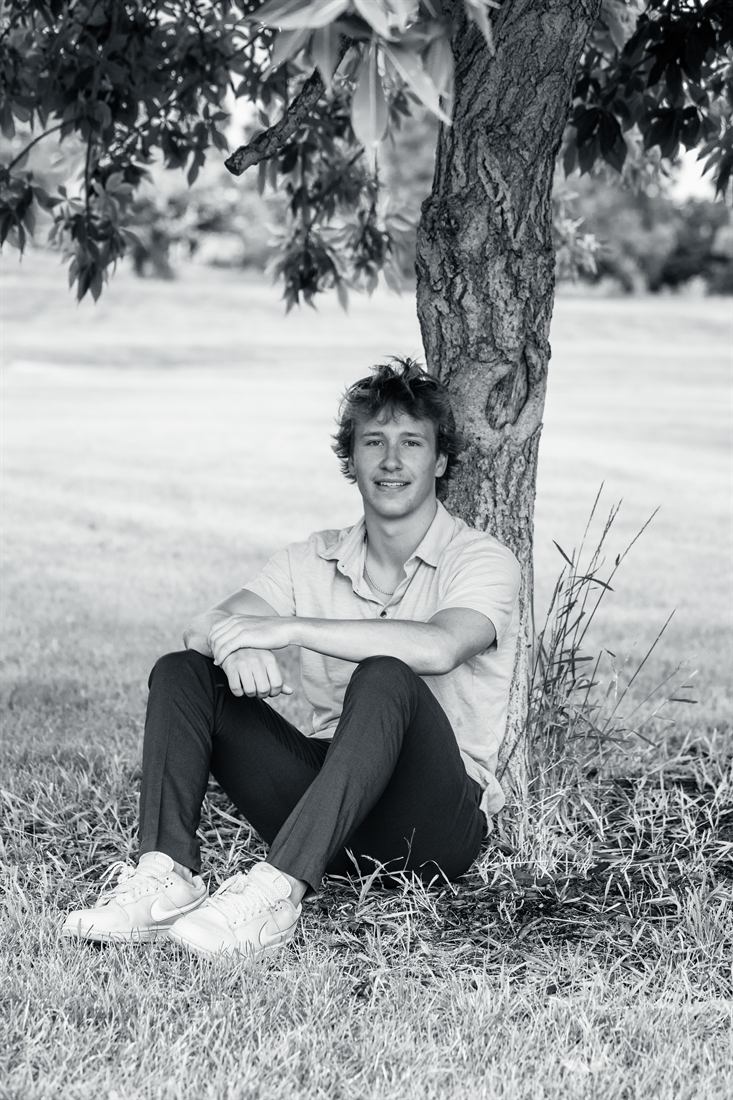 Black and white senior portrait beneath a tree